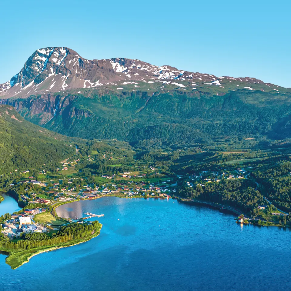Panoramautsikt over Lavangen, omgitt av grønne åser og snødekte fjell.