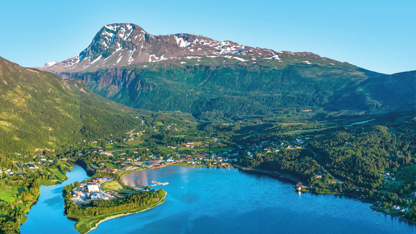 Panoramautsikt over Lavangen, omgitt av grønne åser og snødekte fjell.
